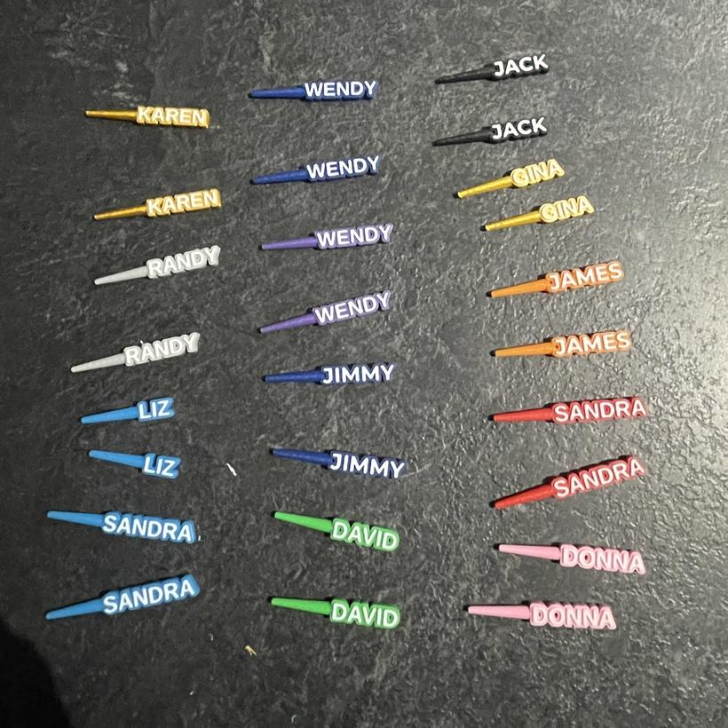 A batch of custom 3D-printed cribbage pegs with names including KAREN, WENDY, JACK, RANDY, LIZ, JIMMY, SANDRA, DAVID, DONNA and JAMES